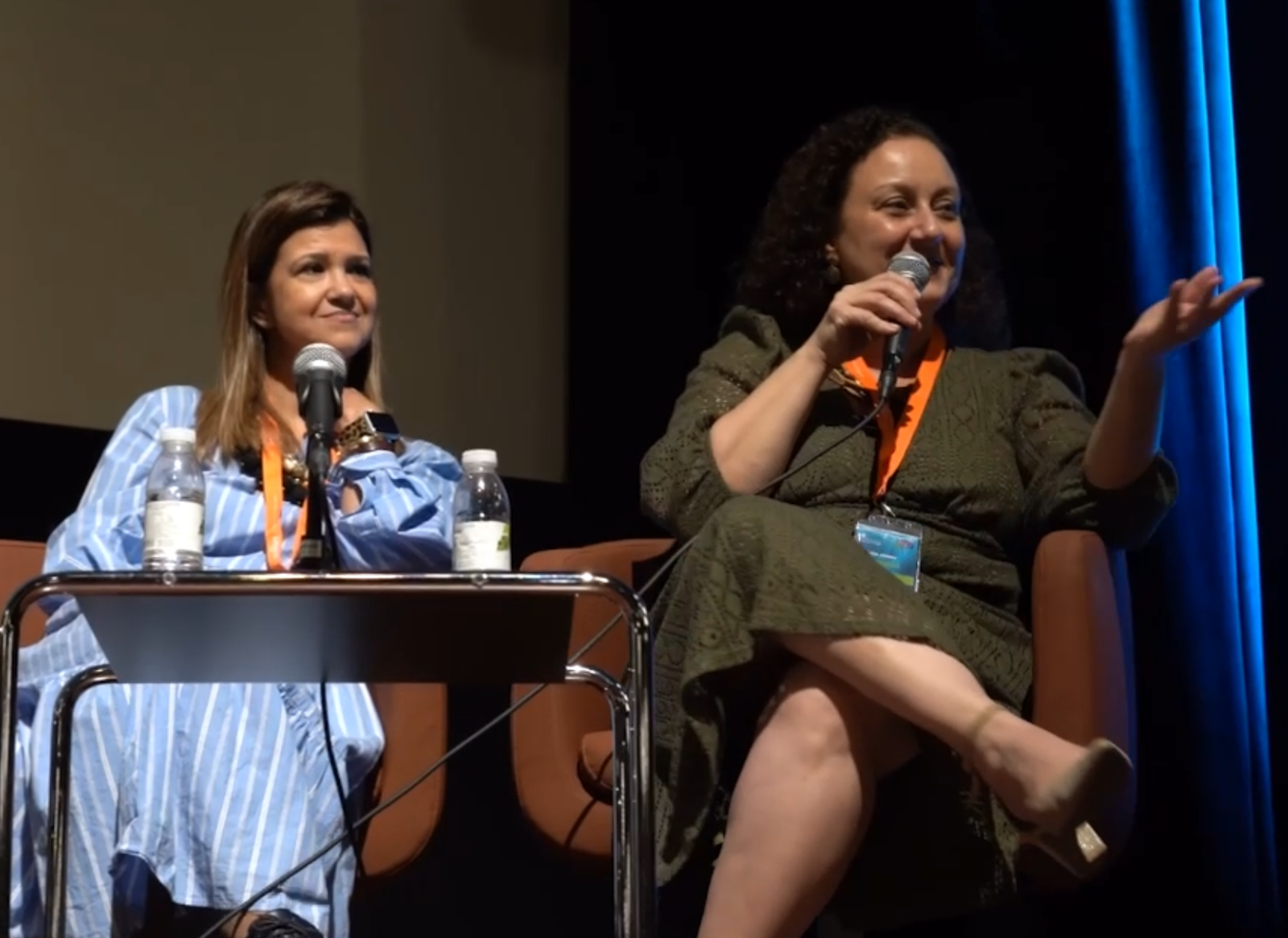 Duas oradoras sentadas em palco, uma delas a falar ao microfone, durante o 1.º Congresso Insular, em 2024.